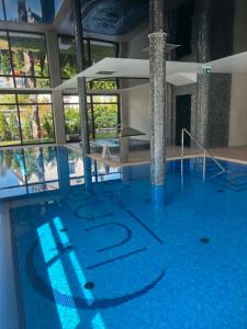 a large swimming pool with blue water in a building at Luna in Niechorze