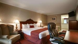 ein Hotelzimmer mit einem Bett und zwei Stühlen in der Unterkunft Best Western Wilderness Trail Inn in Barbourville