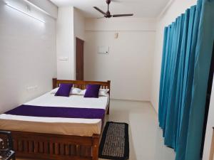 a bedroom with a bed and a blue curtain at Govindha bhavanam 150 meters from Guruvayur temple in Guruvāyūr