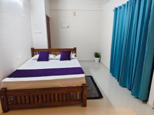 a bedroom with a bed with blue curtains at Govindha bhavanam 150 meters from Guruvayur temple in Guruvāyūr