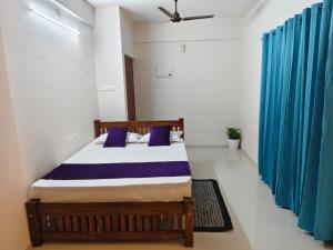 a bedroom with a bed with blue curtains at Govindha bhavanam 150 meters from Guruvayur temple in Guruvāyūr