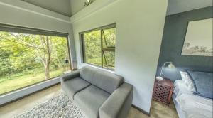 a bedroom with a couch and a bed and a window at Seldom Seen in Malelane