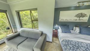 a bedroom with a bed and a chair and window at Seldom Seen in Malelane