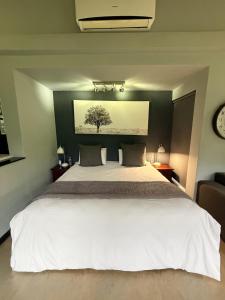 a bedroom with a white bed with a tree on the wall at Seldom Seen in Malelane +16 photos