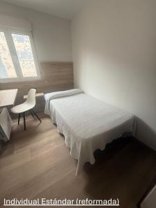 a bedroom with a bed and a chair and a window at Avenida Gijón Centro in Gijón