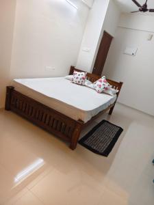 a bedroom with a bed with white sheets and floral pillows at Govindha bhavanam 150 meters from Guruvayur temple in Guruvāyūr +3 photos