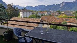 a table with two glasses on a balcony with mountains at Alpine Apartment in Villeneuve