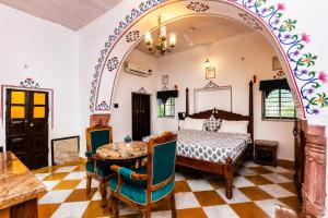 a bedroom with a bed and a table and chairs at Alivaa Heritage Lotwara Fort - Near Shri Mehandipur Balaji Temple in Dausa