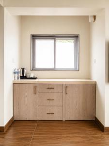 a kitchen with wooden cabinets and a window at Nivaara by GHD Hotels in Nerul