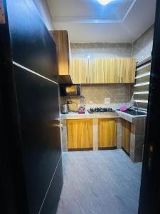 a kitchen with wooden cabinets and a black refrigerator at April shortlet apartments in Lagos +7 photos