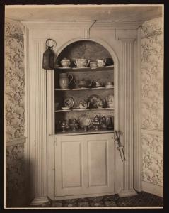 an old photo of a door with a shelf with dishes at JOSIAH KEITH HOUSE museum & inn in Five Corners