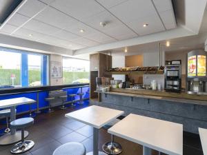 a restaurant with tables and chairs and a counter at Hotel Ibis Budget Vichy in Bellerive-sur-Allier