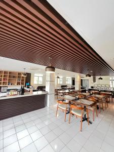 a restaurant with tables and chairs and a kitchen at Hotel Imam Bonjol by Benhas in Padang