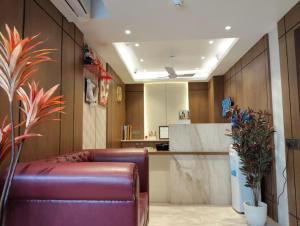 a lobby with a brown leather couch and a kitchen at Eennra Ssubarna in Baharampur