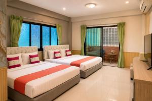 two beds in a hotel room with a television at Fortune Pattaya Resort in Jomtien Beach