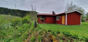 a small red house on a grassy field at Sona Camping in Hegra