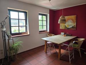 a dining room with a wooden table and two windows at idyllisches Mühlengebäude in Hillesheim