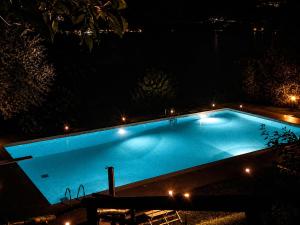 a large blue swimming pool at night with lights at Casa PG - Appartamento Vista Lago in Monte Isola