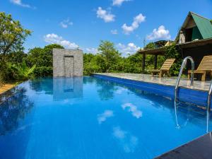 a swimming pool with blue water and two chairs at Lion Rock Haven Cabana in Sigiriya
