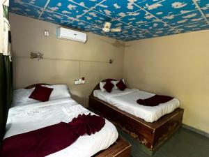 two beds in a room with a ceiling decorated with birds at Rapti Resort in Jhawāni