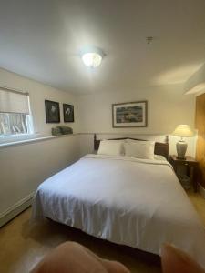 a bedroom with a large white bed and a window at Cambie Guestshouse in Vancouver
