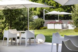 a patio with white chairs and tables and umbrellas at Blu Hotel Natura & Spa - Adults Only in Folgaria +37 photos