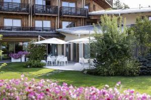 a building with tables and umbrellas in a yard at Blu Hotel Natura & Spa - Adults Only in Folgaria