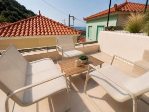 a balcony with white chairs and a wooden table at Kayani View in Taxiárkhai