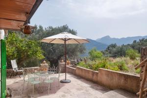 a patio with an umbrella and tables and chairs at Can Carabá in Illes Balears
