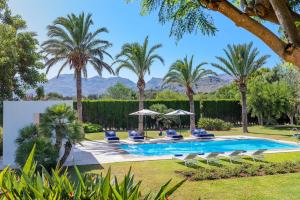 a pool with chairs and palm trees at Finca Playa Llenaire - Can Pou in El Port