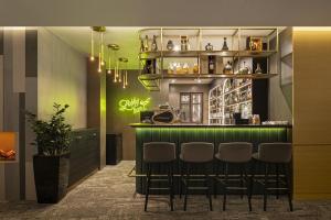 a bar in a restaurant with green walls and stools at Avalon Resort & SPA in Miskolctapolca