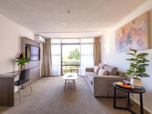 a living room with a couch and a table at Auckland Rose Park Hotel in Auckland