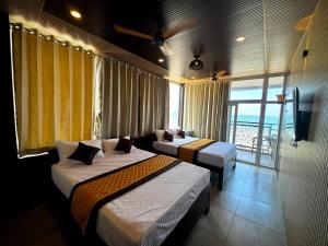a hotel room with two beds and a balcony at Serenity Beach Inn in Pondicherry +51 photos