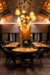 a restaurant with wooden tables and chairs and chandeliers at Avalon Resort & SPA in Miskolctapolca