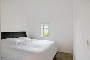 a white bed in a white room with a window at HollyWad in Holwerd