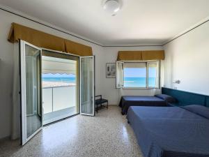 a bedroom with two beds and a balcony with the ocean at Hotel Excelsior in Fano