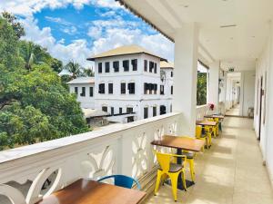 un balcone con tavoli e sedie e un edificio di Panda Hostel a Zanzibar City