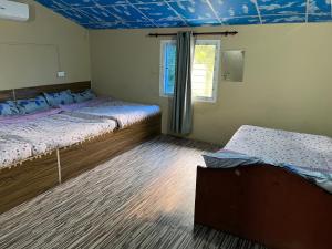 a bedroom with two beds and a blue ceiling at Rapti Resort in Jhawāni +15 photos