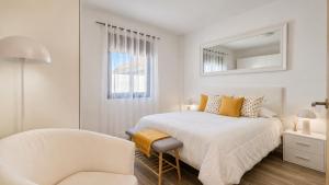 a white bedroom with a bed and a chair at JVG VILLAS - Villa Joval in Güimar