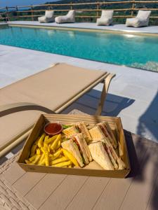 a tray of sandwiches and french fries next to a pool at Wild Cretan West in Drakiana