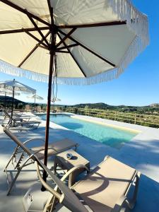 a pool with an umbrella and chairs and a swimming pool at Wild Cretan West in Drakiana