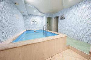 a bathroom with a large tub with blue tiles at Pensiune Taviada in Chişinău