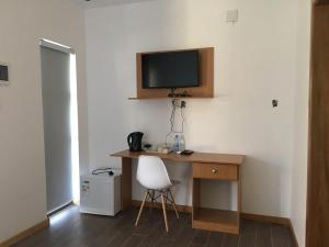 a room with a desk with a television and a chair at HOTEL GANI in Manjacaze