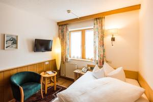 a hotel room with a bed and a chair at Hotel Walserberg in Warth am Arlberg
