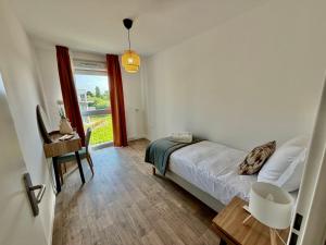 a bedroom with a bed and a table and a window at DOMITYS - Les Cerfs-Volants in Berck-sur-Mer