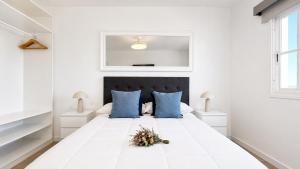 a white bedroom with a large white bed with blue pillows at JVG VILLAS - Villa Valeria in Güimar