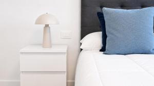 a bed with a blue pillow and a lamp on a night stand at JVG VILLAS - Villa Valeria in Güimar +28 photos