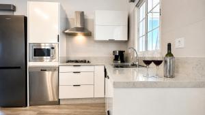 a kitchen with white cabinets and a bottle of wine at JVG VILLAS - Villa Valeria in Güimar