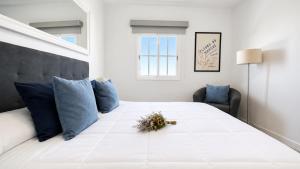 a bedroom with a large white bed with blue pillows at JVG VILLAS - Villa Valeria in Güimar