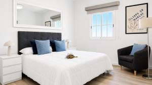 a white bedroom with a large bed and a chair at JVG VILLAS - Villa Valeria in Güimar